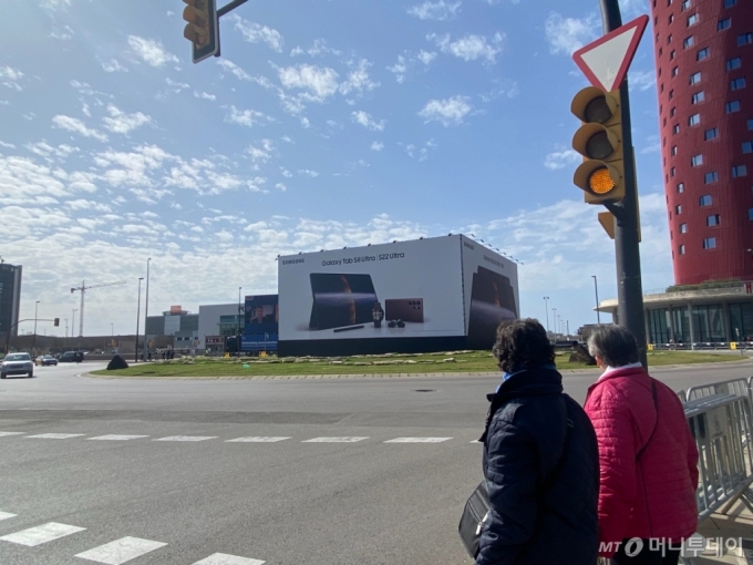 MWC 2022 전시장 바로 앞 교차로에 위치한 삼성전자 갤럭시 옥외광고판을 시민들이 지켜보고 있다. /사진=김수현 기자.