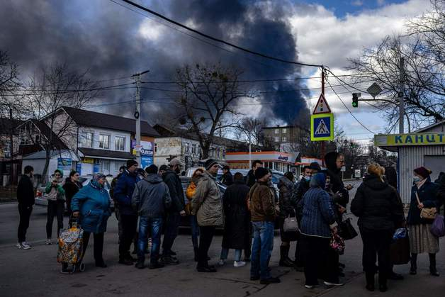 (바실키프 AFP=뉴스1) 우동명 기자 = 27일 (현지시간) 우크라니아 수도 키예프 외곽 바실키프에 위치한 원유 저장소가 러시아 군의 야간 공습으로 연기가 솟아오르는 동안 주민들이 슈퍼마켓 앞에 줄을 서 있다.  (C) AFP=뉴스1  