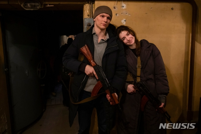 [크이우=AP/뉴시스] 25일(현지시간) 우크라이나 수도 크이우에서 한 신혼부부가 결혼한 지 하루 만에 도시 방위군에 합류한 뒤 소총을 들고 기념촬영을 하고 있다.
