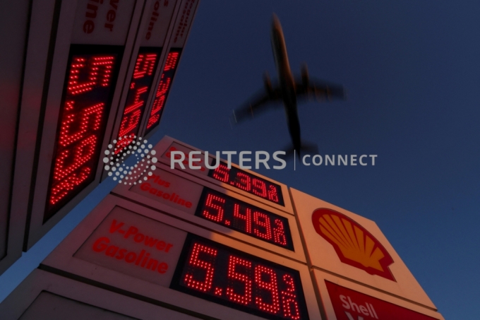 An aircraft flies over a sign displaying current gas prices as it approaches to land in San Diego, California, U.S., February 28, 2022. REUTERS/Mike Blake/File Photo