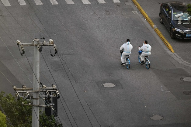 9일(현지시간) 코로나19 전면 봉쇄령이 내려진 중국 상하이의 텅 빈 거리에 방역요원들이 자전거를 타고 있다. / AFP=뉴스1 