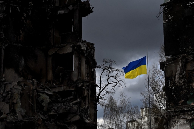 17일(현지시간) 우크라이나 키이우의 한 마을에서 러시아군의 공격으로 파괴된 건물 사이에 우크라이나 국기가 펄럭이고 있다./사진=AFP