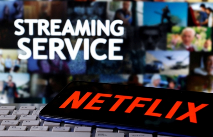 A smartphone with the Netflix logo is seen on a keyboard in front of displayed &quot;Streaming service&quot; words in this illustration taken March 24, 2020. REUTERS/Dado Ruvic/File Photo