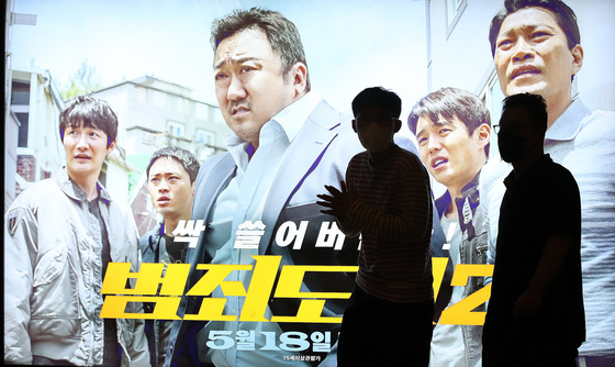지난 12일 서울 CGV용산아이파크몰에서 ‘범죄도시2’ 포스터 앞으로 영화팬들이 지나가고 있다./사진=뉴스1
