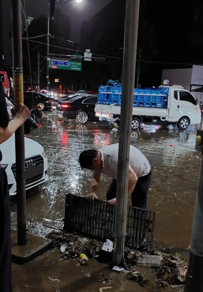한 남성이 8일 강남역 근처에서 빗물받이 덮개를 열고 안에 있는 쓰레기를 맨손으로 건져내고 있다 /사진=온라인 커뮤니티