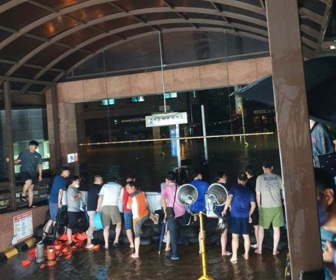 지난 10일 많은 비가 내린 충북 청주시 흥덕구 복대동의 한 아파트 주민들이 지하주차장 침수를 막기 위해 차수막 밖으로 물을 퍼내고 있다 /사진=온라인 커뮤니티