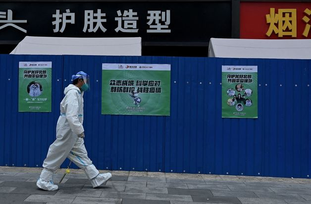 (베이징 AFP=뉴스1) 우동명 기자 = 20일 (현지시간) 중국 베이징 코로나19 통제 구역의 펜스가 설치된 주거지를 방역요원이 걸어 가고 있다.   (C) AFP=뉴스1  