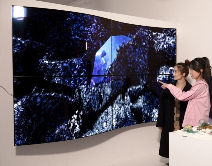 28일(현지시간) 영국 런던에서 열린 디지털아트展 '루미너스(Luminous)에서 관람객들이 LG디스플레이의 55인치 커브드 OLED 패널 4대를 상하좌우로 이어붙여 만든 작품명 ‘보이지 않는 혁신(Invisible Reinvention)’을 감상하고 있다./사진제공=LG디스플레이