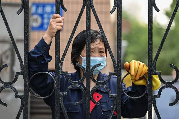 (상하이 AFP=뉴스1) 우동명 기자 =  25일(현지시간) 코로나19 봉쇄령이 내려진 중국 상하이의 통제 구역 내에서 근로자가 펜스 밖을 내다보고 있다.  (C) AFP=뉴스1  