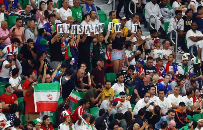 29일(현지시간) 카타르 도하 알투마마 스타디움에서 열린 월드컵 조별리그 B조 이란 대 미국 경기에서 이란 응원석 관중들이 히잡을 쓰지 않았다는 이유로 끌려가 의문의 죽음을 당한 여성 '마흐사 아미니'의 이름이 적힌 종이를 들고 있다./로이터=뉴스1 