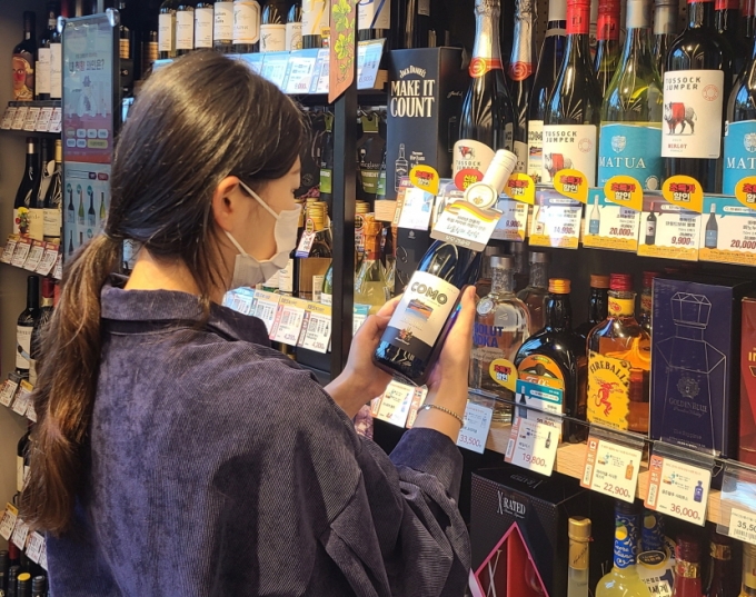 고객이 이마트24 매장에서 꼬모 와인 상품을 살펴보고 있는 모습 /사진=이마트24