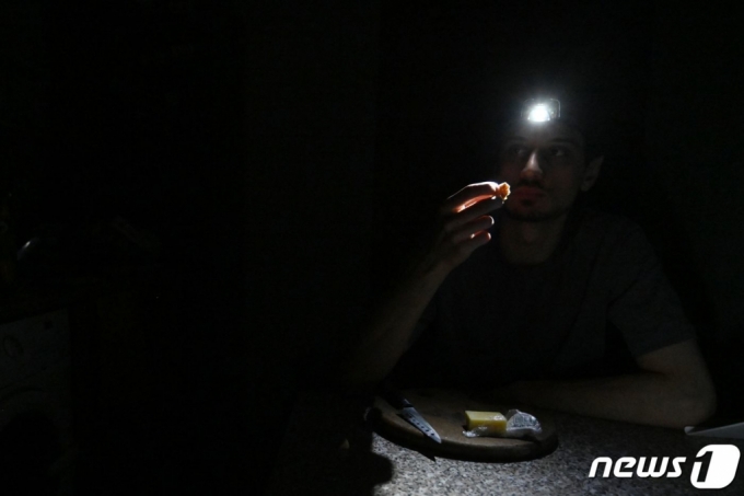 11일(현지시간) 러시아의 침공으로 정전이 된 우크라이나 키이우에서 주민이 음식을 먹기 위해 머리 전등을 쓰고 있다. /AFPBBNews=뉴스1