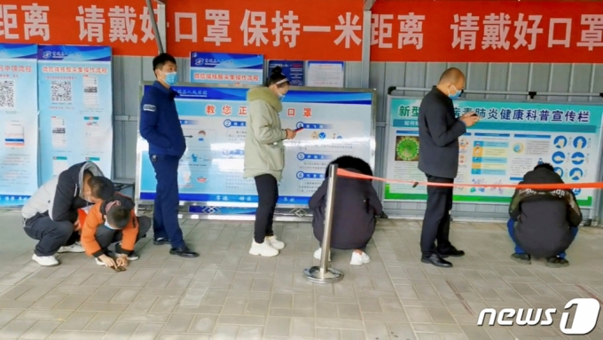 2022년 12월 15일 (현지시간) 중국 허난성 신양에 마련된 코로나19 검사소에 주민들이 검사를 기다리며 줄을 서 있다.  /로이터=뉴스1
