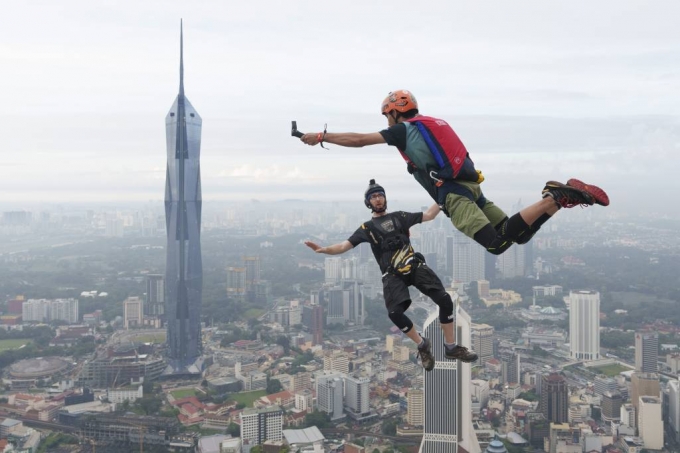 [쿠알라룸푸르=AP/뉴시스] 3일(현지시간) 말레이시아 쿠알라룸푸르에서 쿠알라룸푸르(KL) 타워 국제 점프대회가 열려 베이스(BASE) 점핑 선수들이 뛰어내리고 있다. 'BASE'는 건물(Buildings), 안테나(Antennas), 교량(Spans), 지구(Earth)를 나타내는 것으로 지상의 높은 건물이나 절벽 등에서 낙하산으로 강하하는 매우 위험한 익스트림 스포츠다. 2023.02.03.