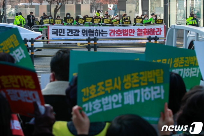 대한간호협회와 대한의사협회가 지난달 9일 서울 여의도 국회의사당 앞 맞은편에서 각각 간호법 제정 촉구-제정 반대 손팻말을 들고 있다./사진= 뉴스1