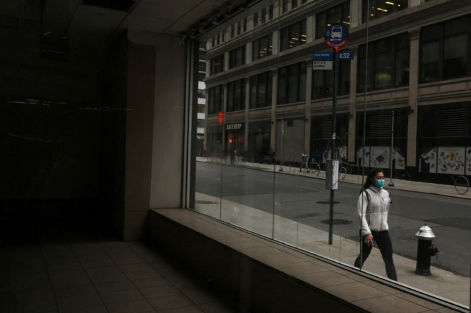 뉴욕의 미드타운 맨해튼에서 한 여성이 마스크를 쓰고 텅 빈 상업용 부동산 앞을 지나가고 있다. /로이터=뉴스1