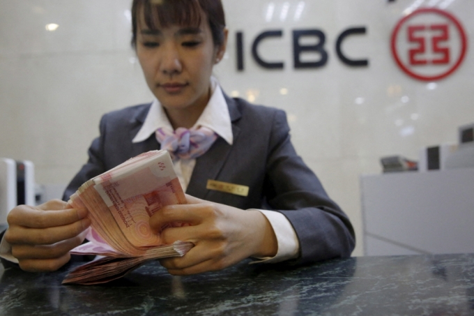 중국공상은행(ICBC) 직원이 베이징 지점에서 사진 촬영 중 카메라를 향해 포즈를 취하며 중국 100위안 지폐를 세고 있다. /로이터=뉴스1