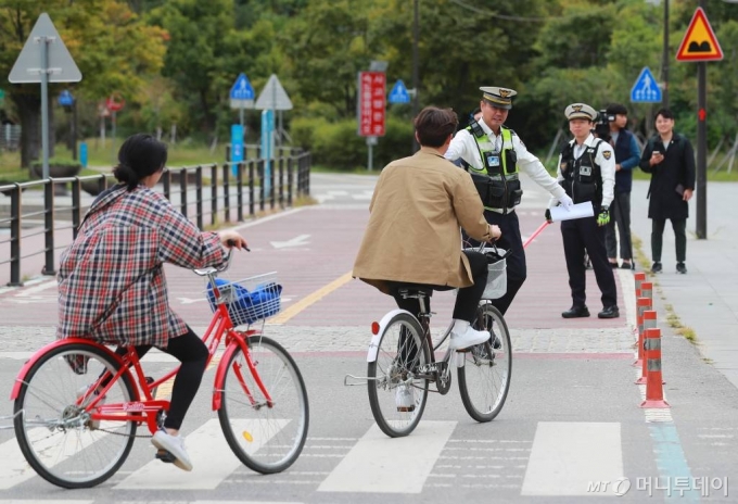 자전거 운전자와 동승자의 안전모(헬멧) 착용 의무화 제도가 시행된 28일 오전 서울 여의도 한강물빛공원 인근에서 경찰이 계도를 위해 안전모 없이 자전거를 타던 시민들을 멈춰 세우고 있다. 자전거 헬멧착용 의무화는 단속·처벌규정이 없는 훈시규정이며 적용 대상 도로는 도로법상 도로와 자전거도로로 한정된다. /사진=이동훈 기자 photoguy@
