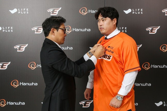 류현진(오른쪽)이 22일 박찬혁 한화 이글스 대표로부터 유니폼을 건네받고 직접 착용하고 있다. /사진=한화 이글스