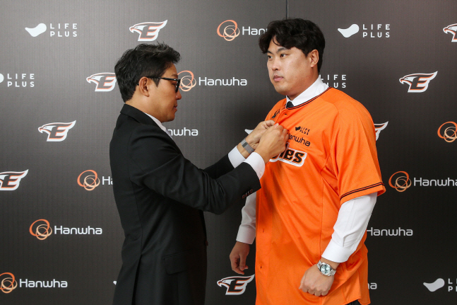 류현진(오른쪽)이 22일 박찬혁 한화 이글스 대표로부터 유니폼을 건네받고 착용하고 있다. /사진=한화 이글스