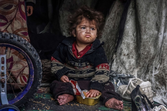 14일(현지시간) 가자지구 라파의 한 난민 캠프에서 팔레스타인 어린이가 임시 탠트에 앉아 배급 받은 음식을 먹고 있다./AFPBBNews=뉴스1