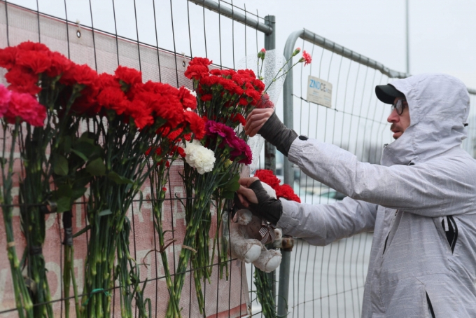 23일 (현지시간) 러시아 모스크바 외곽 크라스노고르스크의 크로커스 시티홀에 무장 괴한들이 총기를 난사해 최소 143명이 숨진 현장서 주민이 헌화를 하고 있다./AFPBBNews=뉴스1