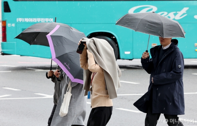 25일 서울 종로구 경복궁 인근에서 시민들이 옷과 우산으로 비를 피하고 있다./사진=뉴스1