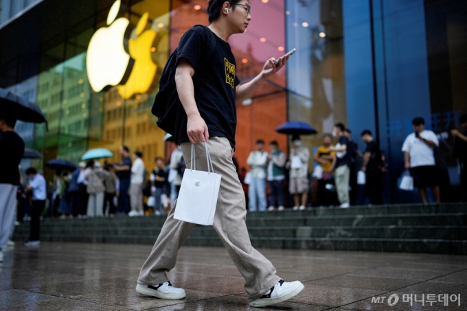 지난해 9월 아이폰15가 중국에서 공식 판매에 돌입한 날 한 남성이 애플 로고가 그려진 종이 가방을 들고 애플 매장 앞을 지나가고 있다. /사진=로이터통신