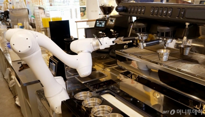 두산로보틱스 협동로봇이 원두가 담긴 포터필터를 커피머신에 장착하고 있다. /사진제공=두산로보틱스