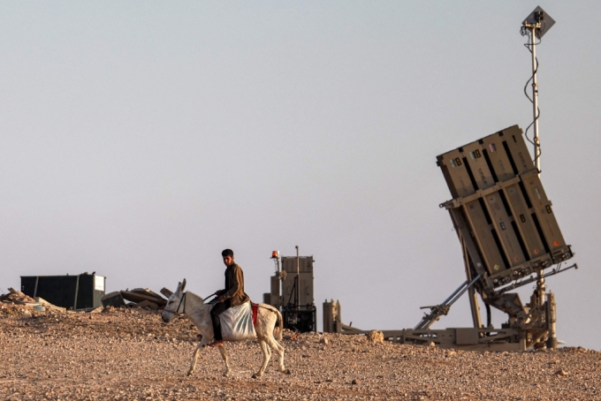 14일(현지시간) 이스라엘 남부 네게브사막 장소 미정의 소재에 배치된 이스라엘군 아이언돔 방공망 포대앞을 당나귀를 탄 한 소년이 지나가고 있다./AFPBBNews=뉴스1