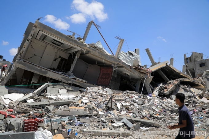 13일(현지시각) 가자지구 남부 칸유니스에서 한 주민이 이스라엘의 공습으로 파괴된 건물 잔해를 바라보고 있다. /신화=뉴시스